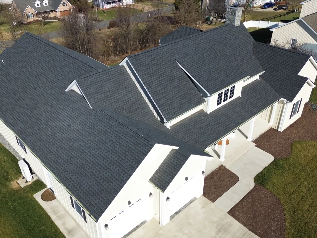 Aerial view of a new home with a finished dark shingle roof, new construction roofing