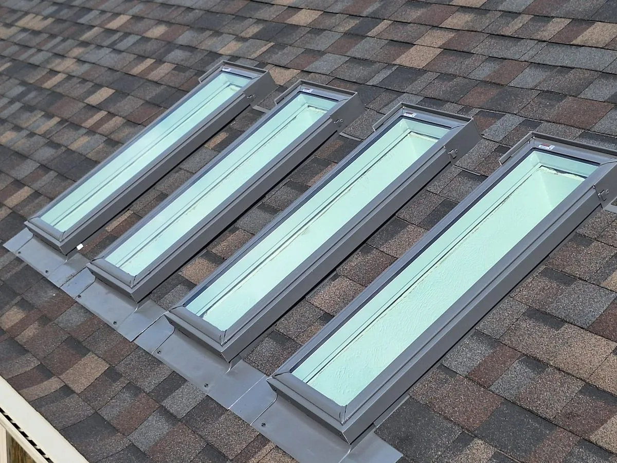 Row of skylights with new metal flashing on an asphalt shingle roof after roof leak repair
