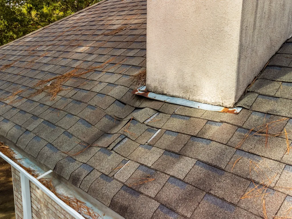 Worn shingles and aging flashing around a chimney, a common spot for roof leak repair