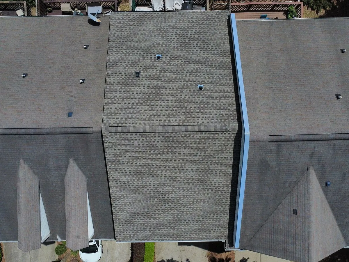 Overhead view of townhouse roofs with one section newly reshingled during roof repair