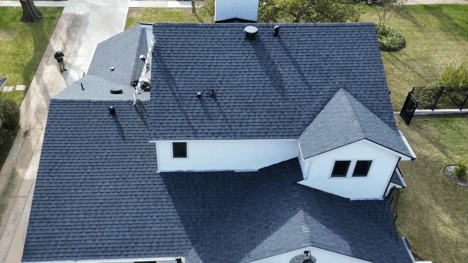 Aerial view of a two story home with a new dark asphalt shingle roof, roofing services